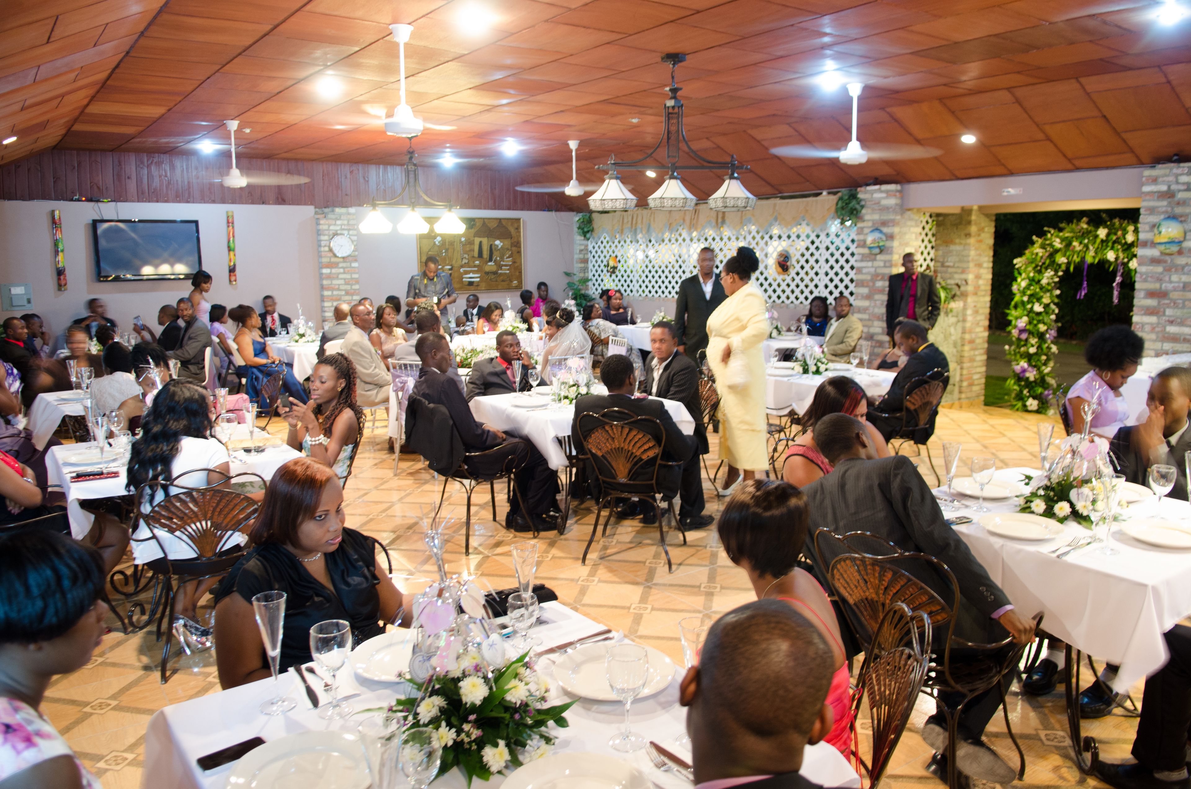 A banquet hall with round tables set for a formal event, featuring white tablecloths and floral centerpieces.