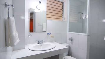 Un baño con lavamanos, espejo y retrete blancos.