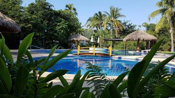 Alberca al aire libre, sombrillas en la alberca y camastros