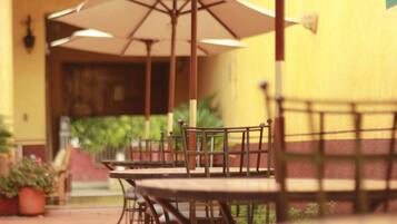 An outdoor patio with tables and chairs, umbrellas, and potted plants.