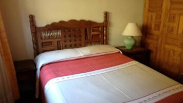 A neatly made bed with a wooden headboard and a green lamp on a bedside table.
