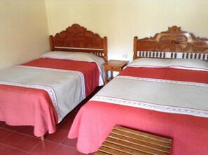Two single beds with wooden headboards, a small wooden nightstand, and a tiled floor.