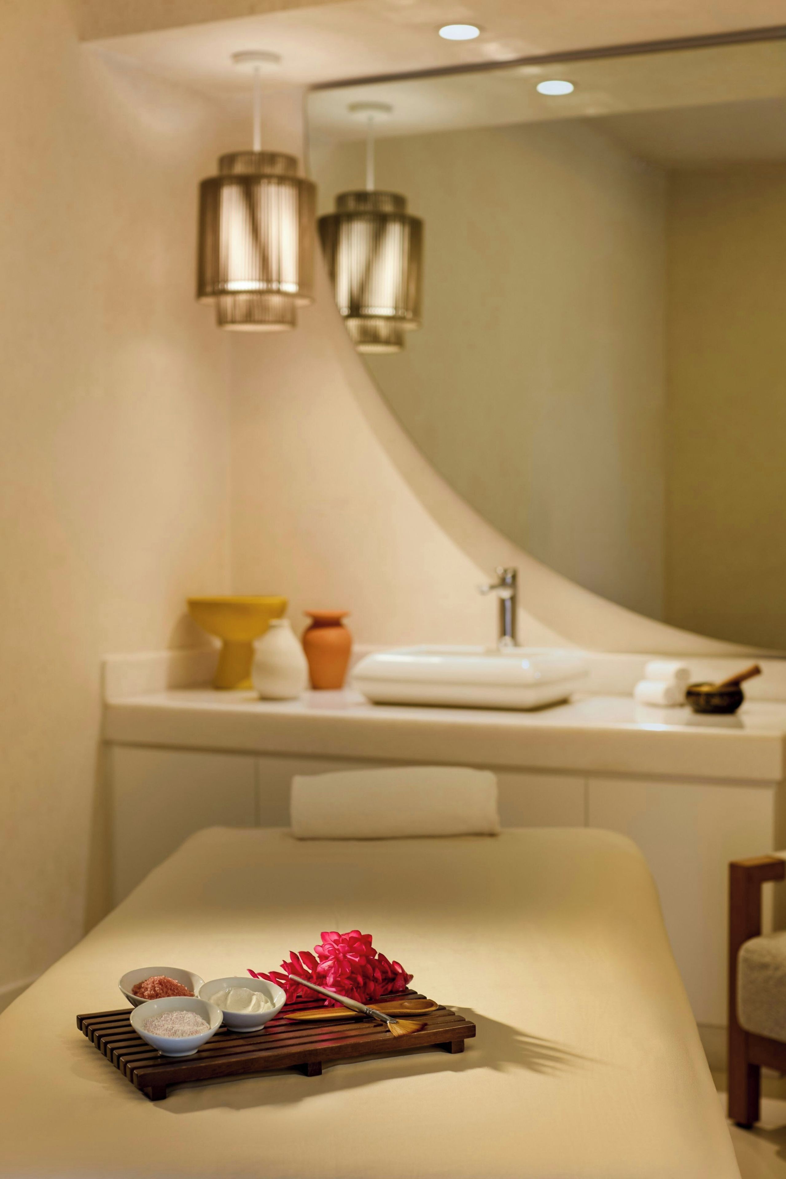 A modern bathroom with a large mirror, a sink, and a massage table with various items on it.
