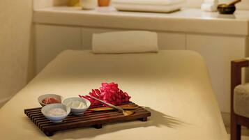 A modern bathroom with a large mirror, a sink, and a massage table with various items on it.