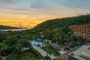 A resort with a pool, palm trees, and a view of the sea at sunset. - JW Marriott Costa Elena Resort & Spa, All-Inclusive (La Cruz)