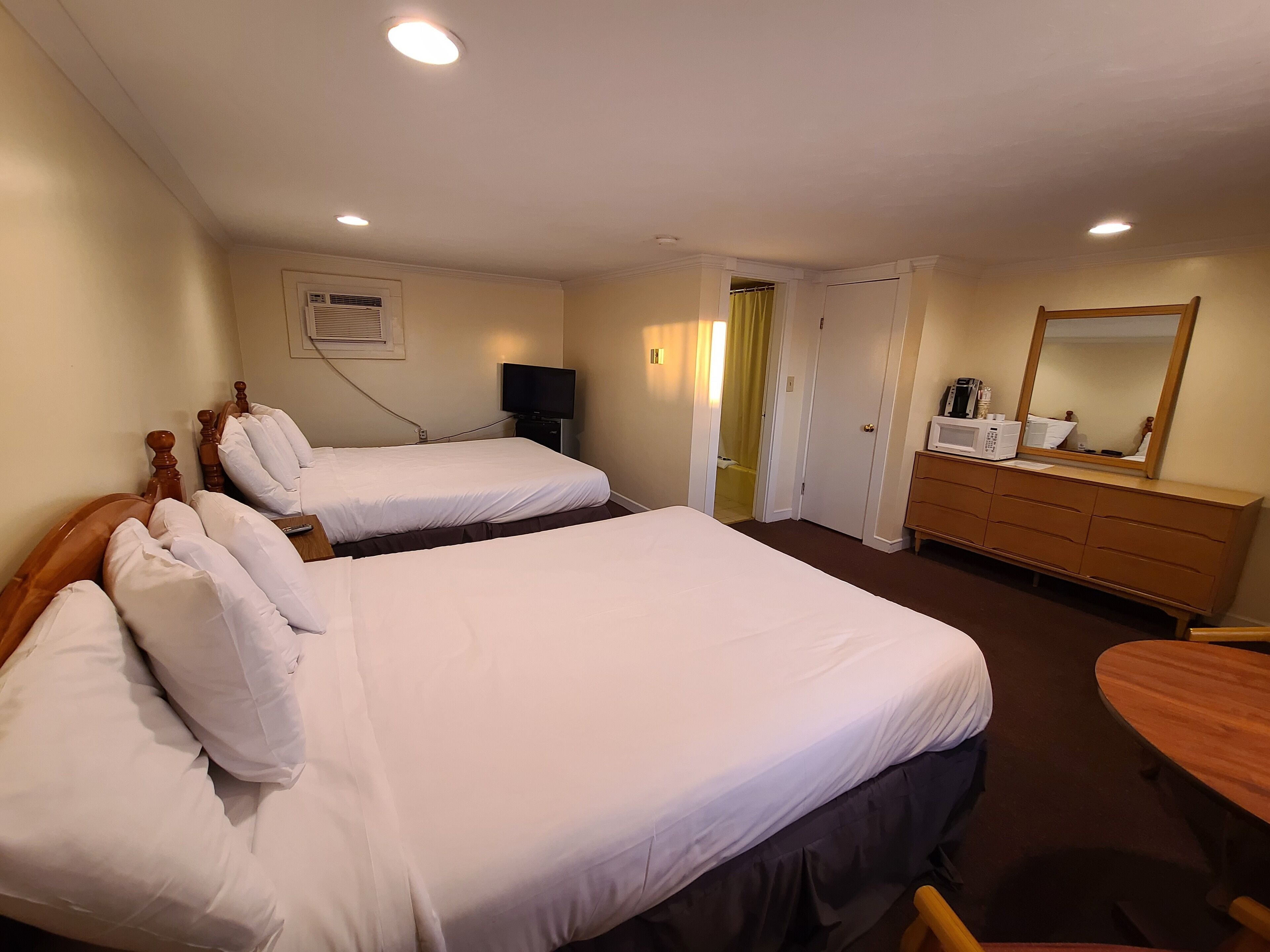 Ett hotellrum med två sängar, en tv, en byrå och en spegel.