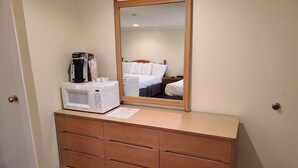 Une chambre d’hôtel avec une commode en bois, un four à micro-ondes et un miroir au-dessus.