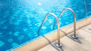 A swimming pool with clear blue water and metal pool ladders. - Country Inn & Suites by Radisson, Bathinda (Bathinda)