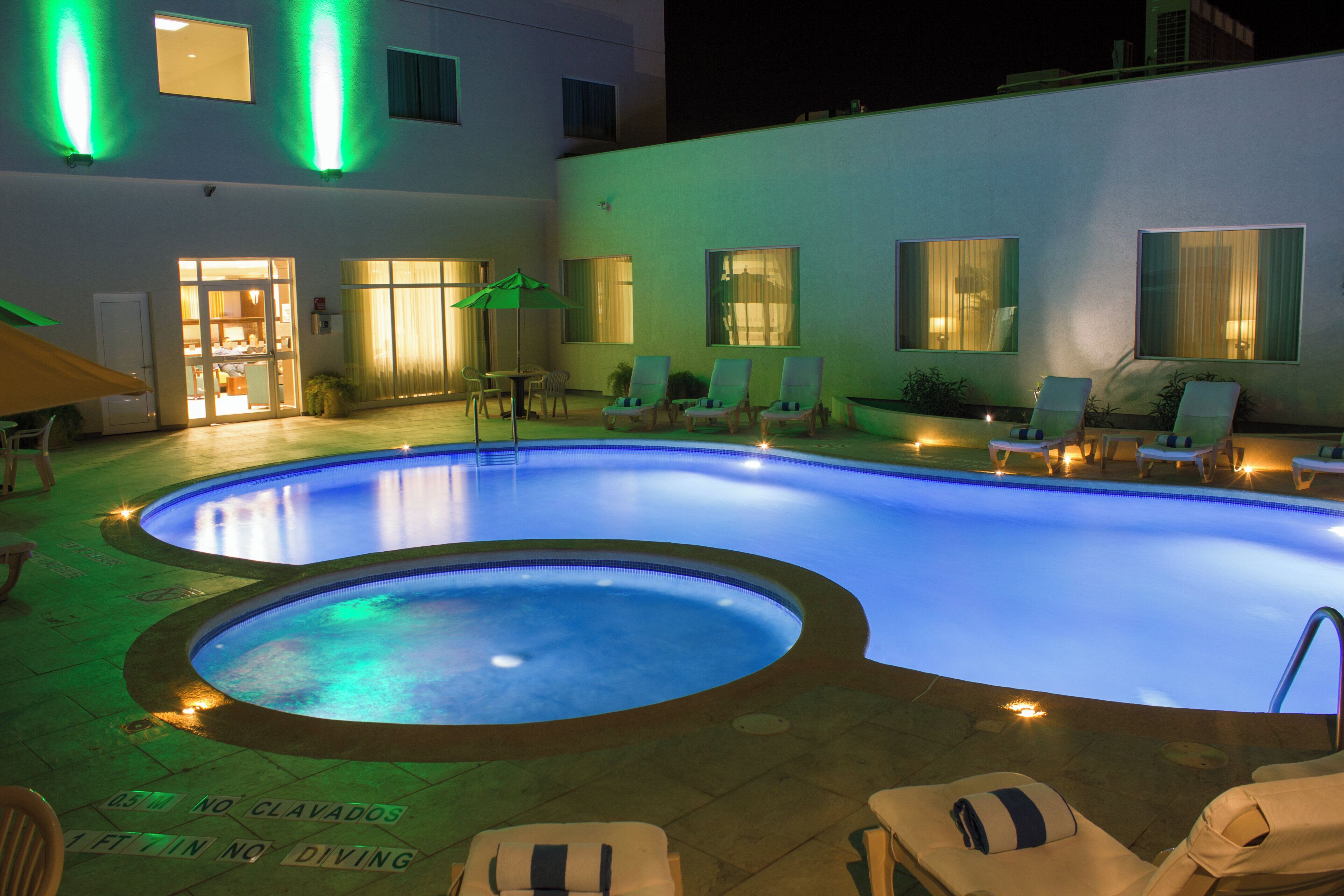 A swimming pool with lounge chairs and a door leading to a room.