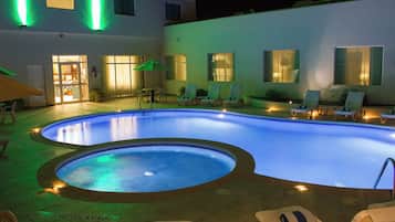A swimming pool with lounge chairs and a door leading to a room.