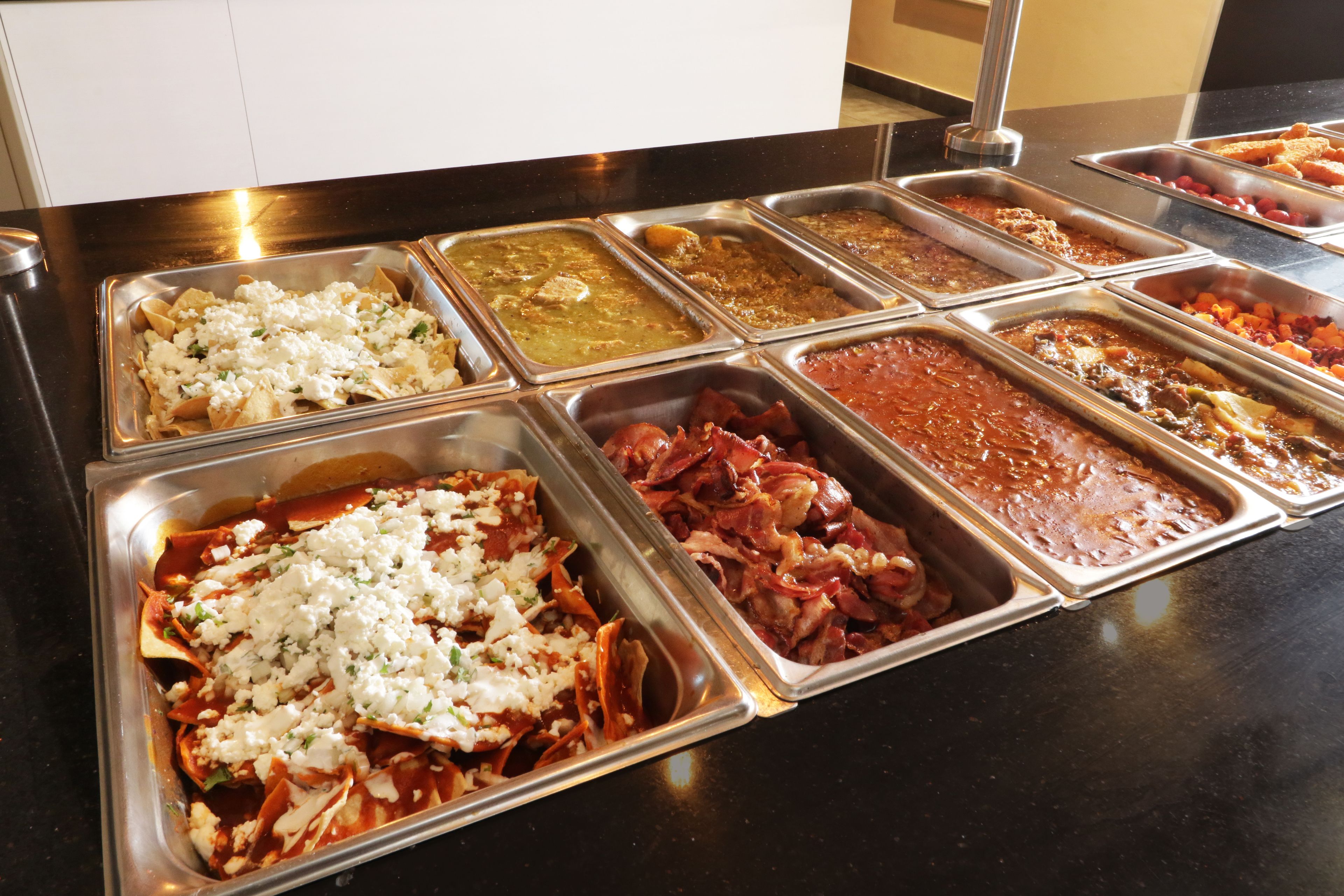 A buffet with various food options including nachos, meats, and different sauces.