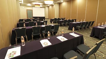 A conference room with rows of tables, chairs, water bottles, and name tags.