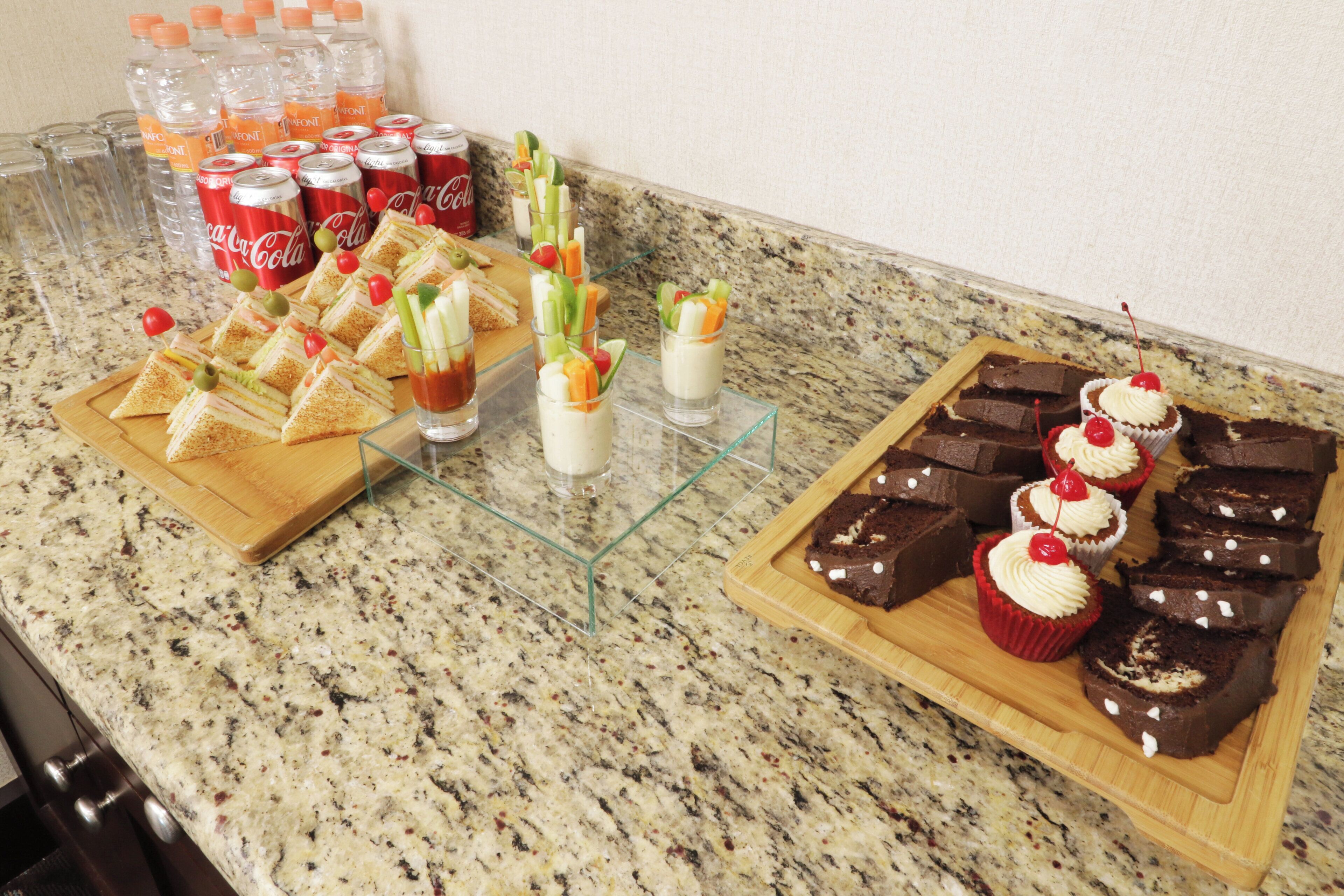 Une table de buffet avec des sandwichs, des boissons et des desserts.