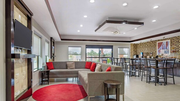 A modern living area with a sectional sofa, a red rug, and a bar area with stools. - Best Western Casino Inn (Vinton)