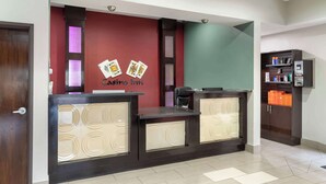 A reception desk with a red and green wall, a casino sign, and a counter with a patterned design. - Best Western Casino Inn (Vinton)