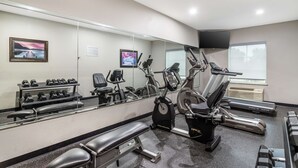 A gym with exercise equipment, a bench, and a mirror reflecting the equipment. - Best Western Casino Inn (Vinton)
