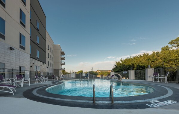 A swimming pool with lounge chairs and a building with multiple floors and balconies. - Holiday Inn Express & Suites Garland E - Lake Hubbard I30 by IHG (Garland)