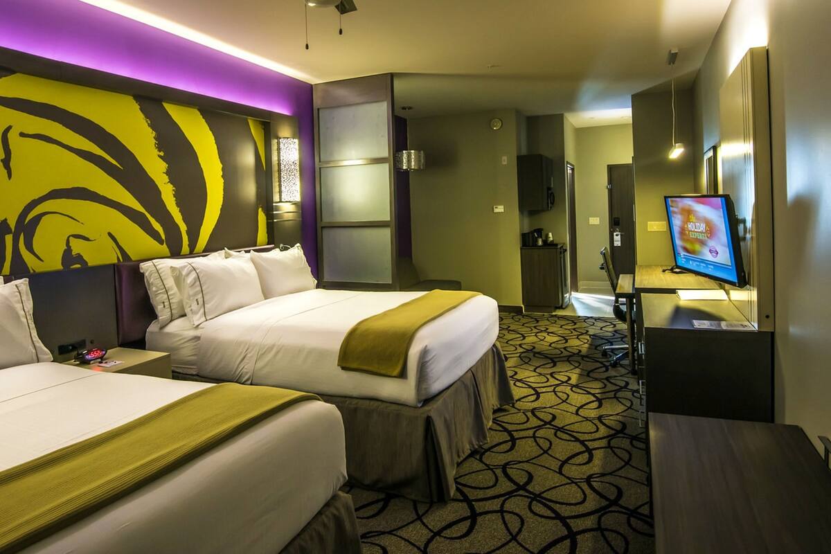 Ein Hotelzimmer mit zwei Betten, einem Fernseher, einer Minibar und einem durch eine offene Tür einsehbaren Badezimmer.
