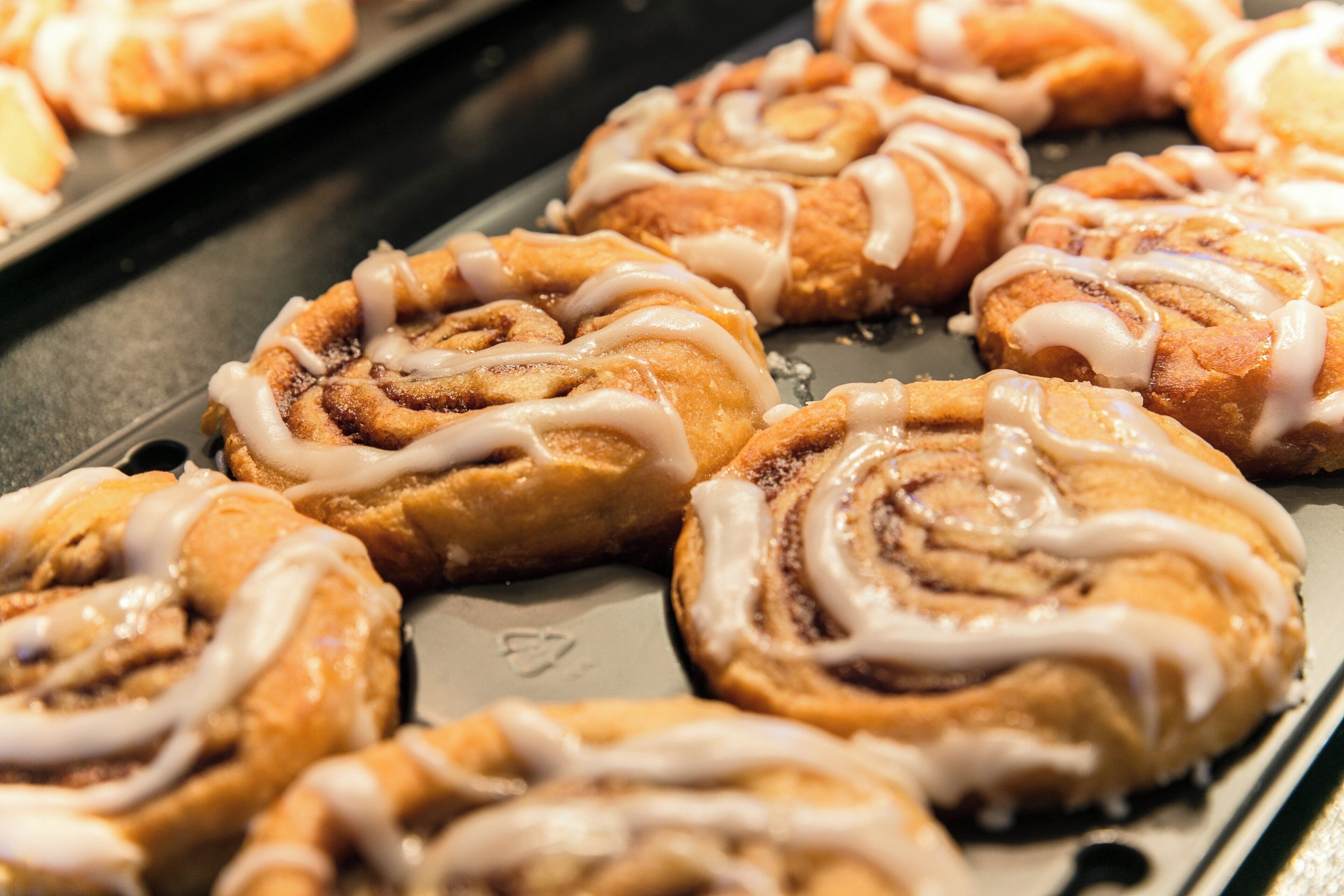 A tray of freshly baked cinnamon rolls with icing.