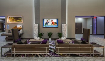 Um saguão moderno com uma grande TV de tela plana, assentos confortáveis e uma mesa de recepção.