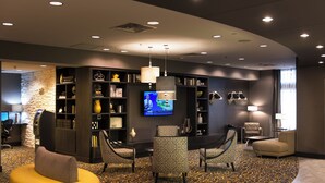 A modern lobby with a curved seating area, a television mounted on the wall, and a stone accent wall. - Holiday Inn Express & Suites Madison Central by IHG (Madison)