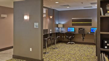A business center with multiple computer stations, a reception desk, and a bookshelf with books.