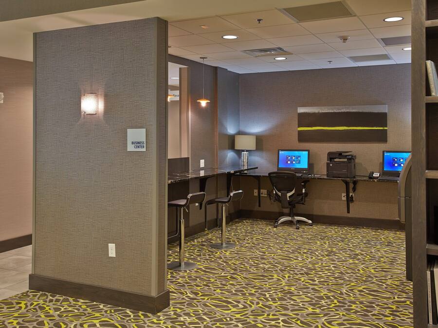 A business center with multiple computer stations, a reception desk, and a bookshelf with books.