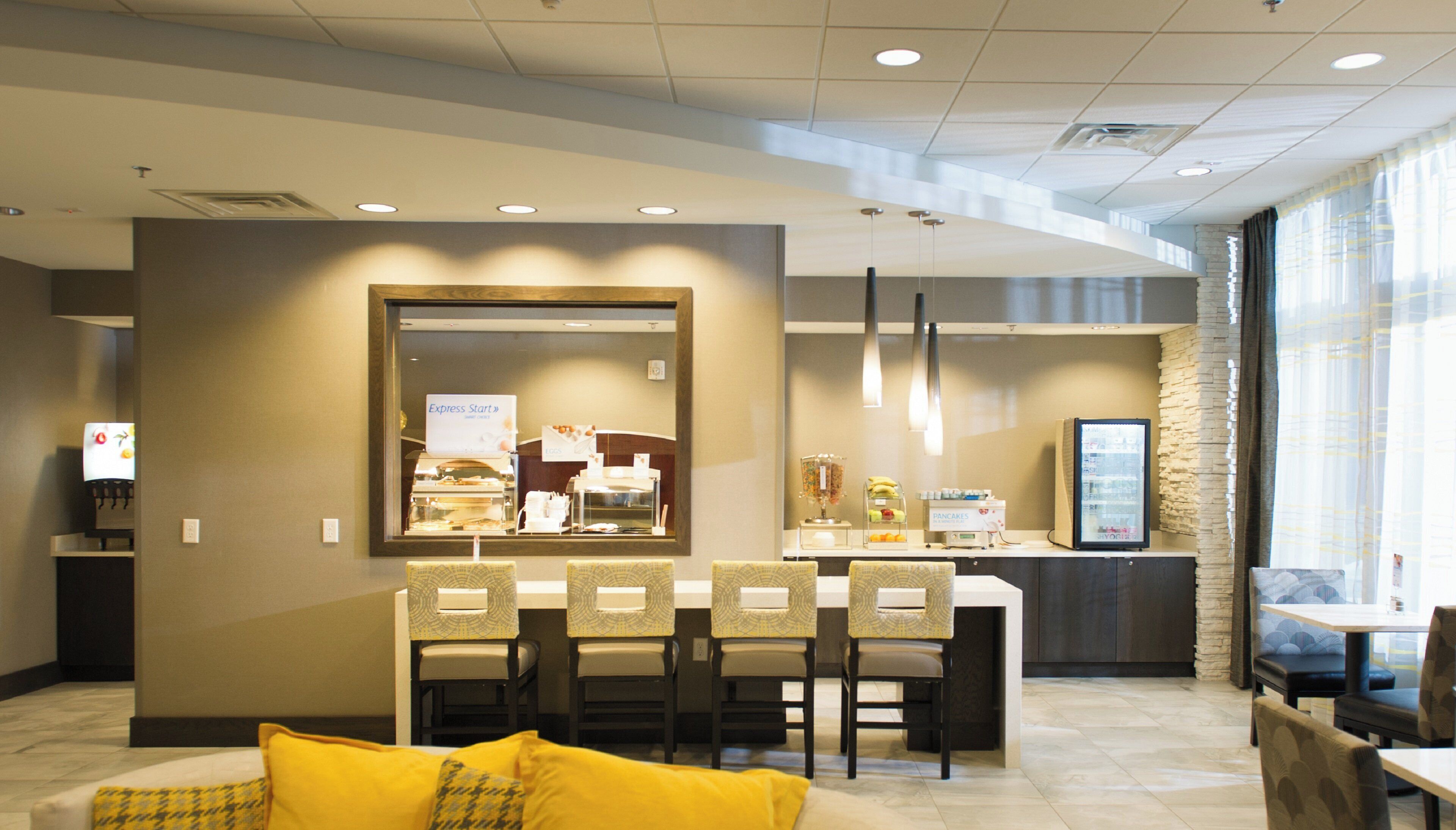 A hotel lobby with a reception desk, seating area, and a coffee station.