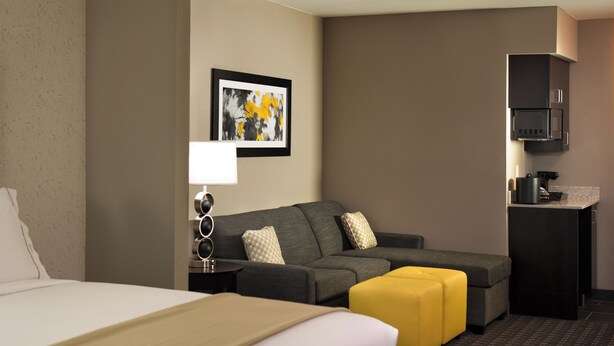 Une chambre d’hôtel avec un lit, un canapé, une machine à café et un tableau encadré au mur.