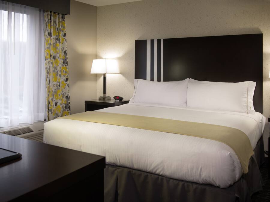 A hotel room with a large bed, two bedside tables with lamps, a desk, and a chair.