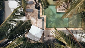 A rooftop pool area with palm trees, a stone pathway, and a small seating area. - Sahari Zanzibar (Bwejuu)