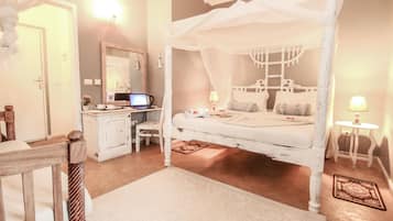 Un dormitorio con cama con dosel, un escritorio con computadora, una silla y una mesita de noche con lámpara.