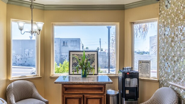 A corner kitchen with a window, a water dispenser, and two patterned chairs. - Continental Lodge (Oakland)
