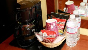 A coffee maker, a basket with cookies, a mug, and water bottles on a table. - Continental Lodge (Oakland)