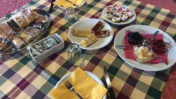 Uma mesa posta com diversos alimentos, incluindo doces, um copo de água e acompanhamentos.