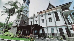 Un edificio de varios pisos con estilo arquitectónico tradicional, que destaca por una torre con tejado puntiagudo.