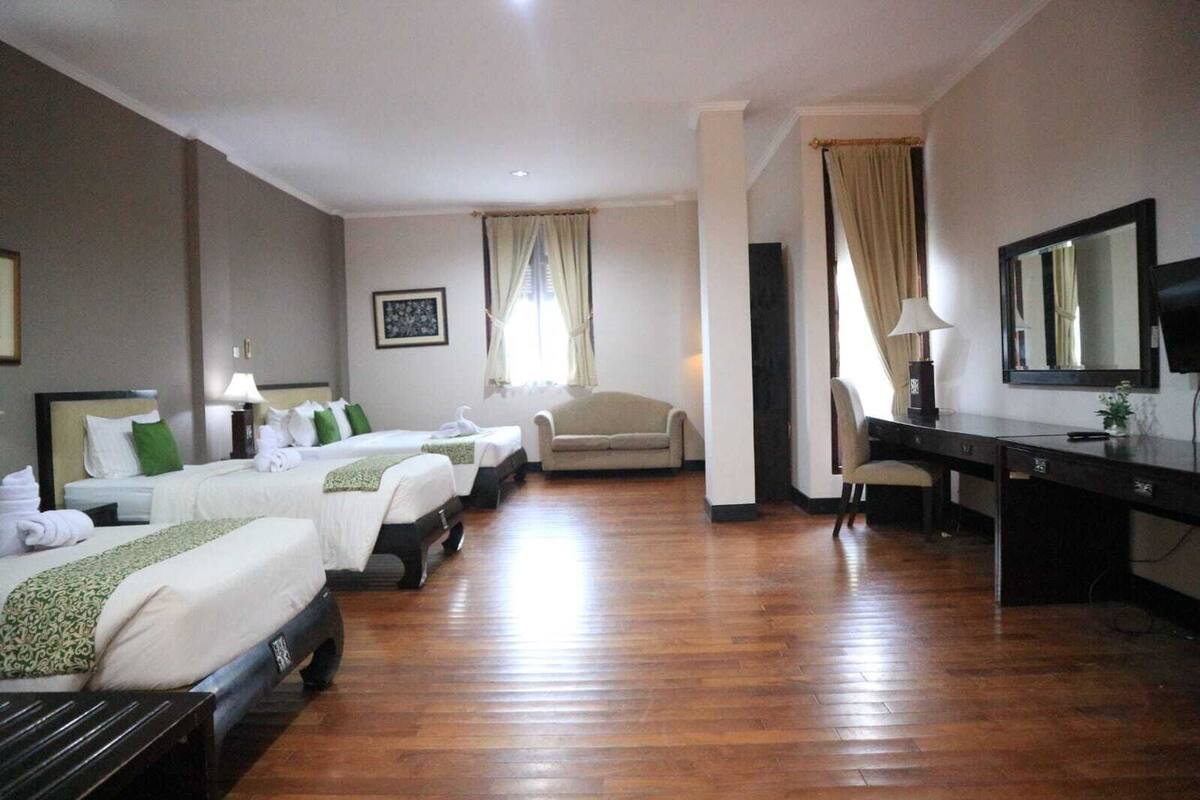 A hotel room with two beds, a desk, a chair, and a sofa.