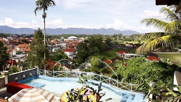 Una piscina con vistas a un pueblo y montañas al fondo.