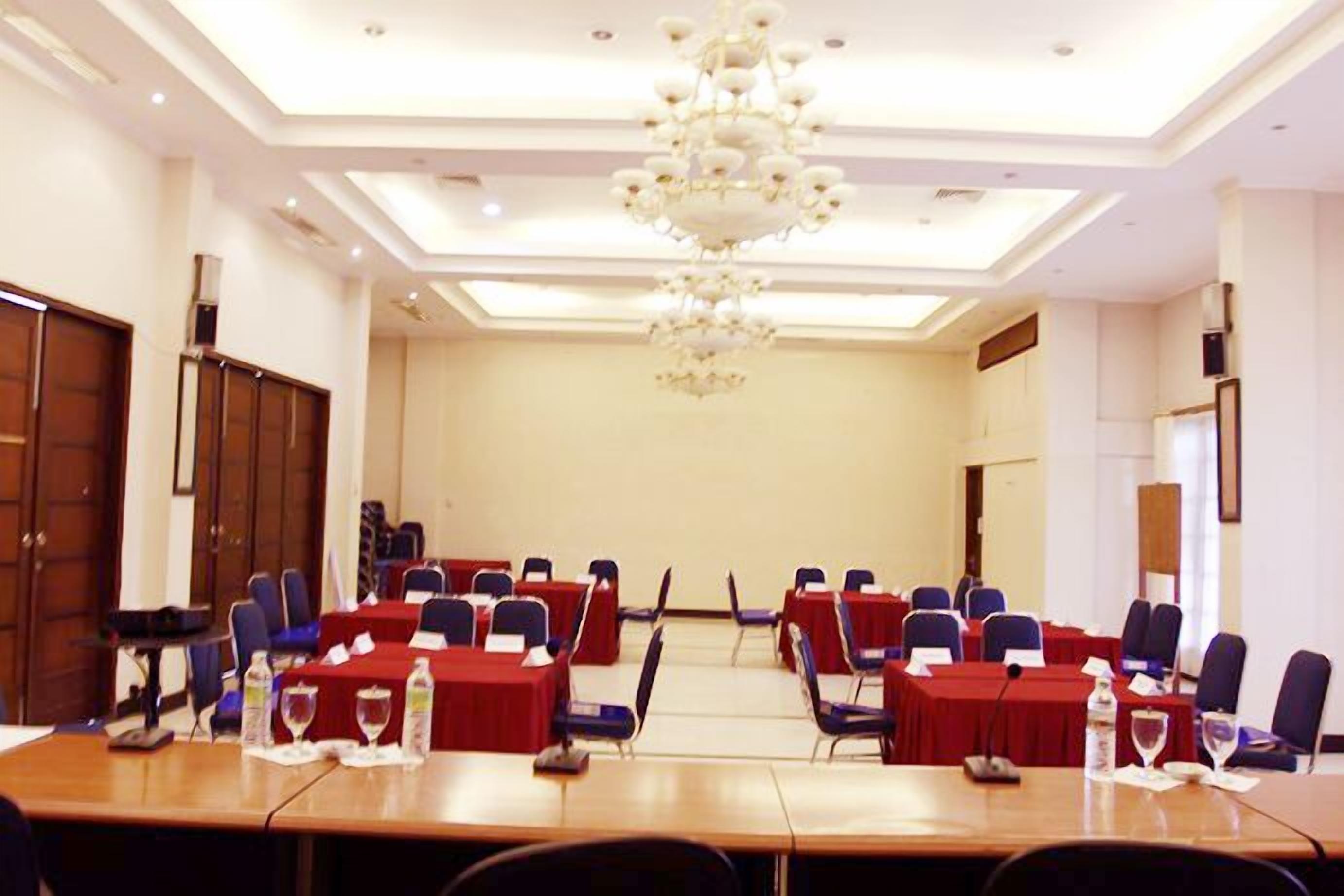 Un salón de conferencias con una larga mesa, varias sillas y un candelabro.