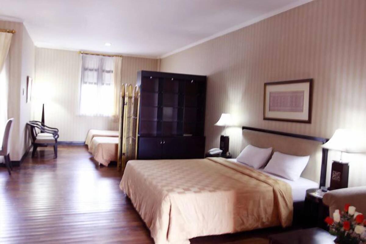 A hotel room with a large bed, a wardrobe, a desk, and a chair.