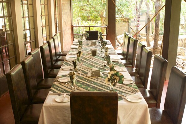 A long dining table set with chairs, a patterned tablecloth, and decorative centerpieces.
