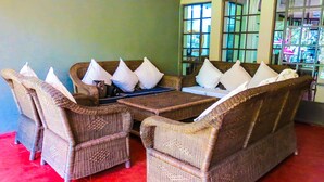 Una habitación con un sofá y sillones de mimbre, una mesita y una ventana con vistas.