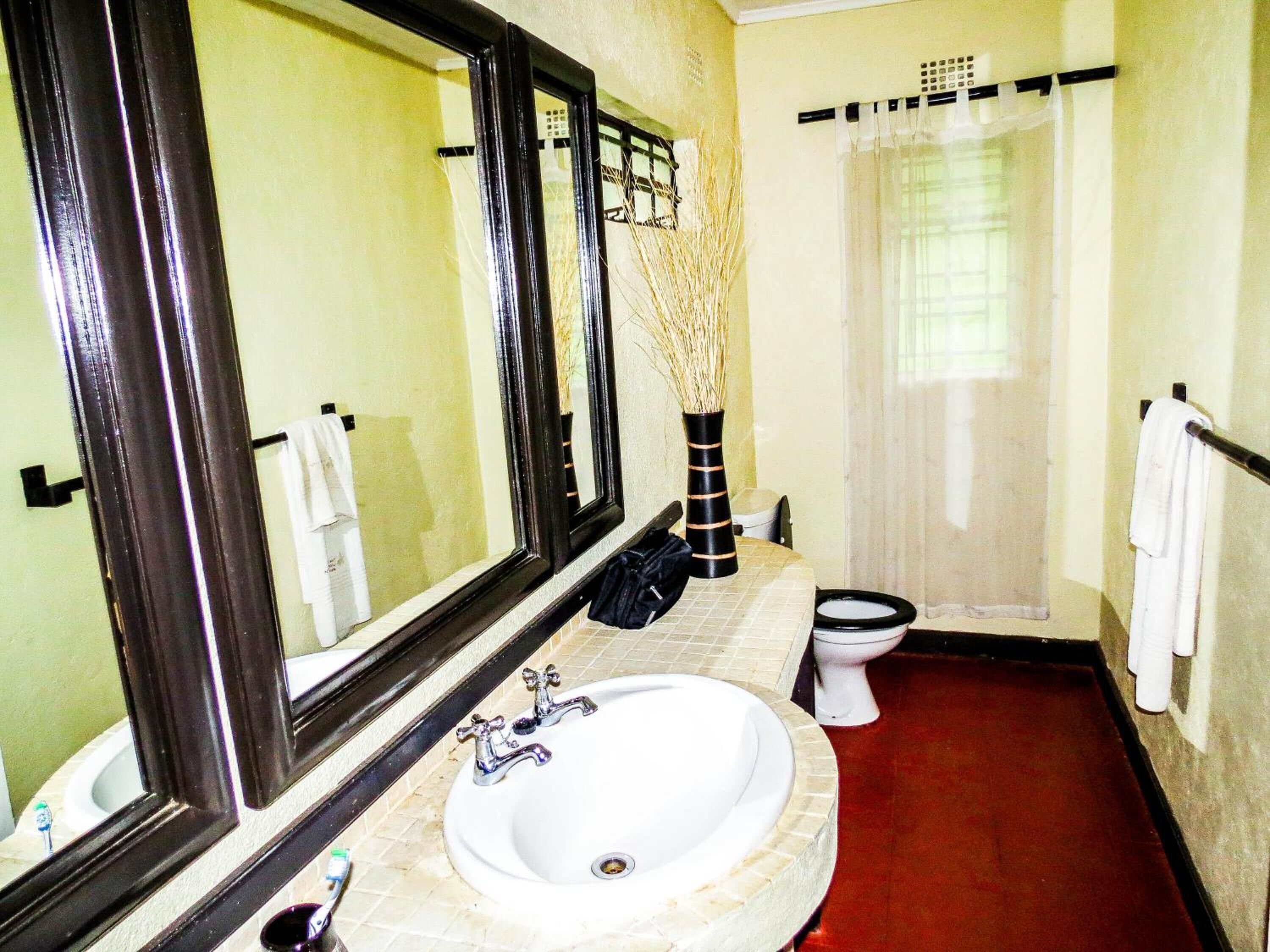 Une salle de bain avec un lavabo blanc, un miroir, des toilettes et un rideau de douche.