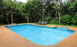 Relax by the pool surrounded by lush greenery and lounge chairs.