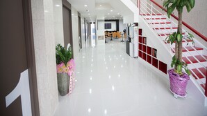 A modern hotel lobby with a polished floor, a staircase with red railings, and potted plants. - Sol Guest House Haeundae (Busan)