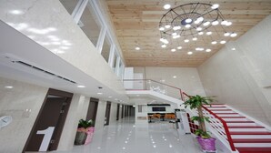 A spacious, modern interior with a high ceiling, a central staircase, and a reception desk. - Sol Guest House Haeundae (Busan)