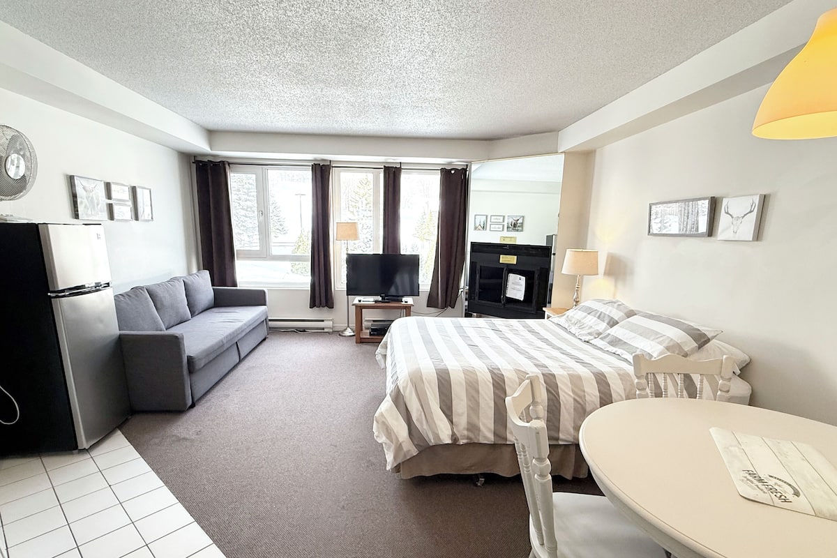 A hotel room with a bed, a sofa, a TV, a desk, and a dining table.