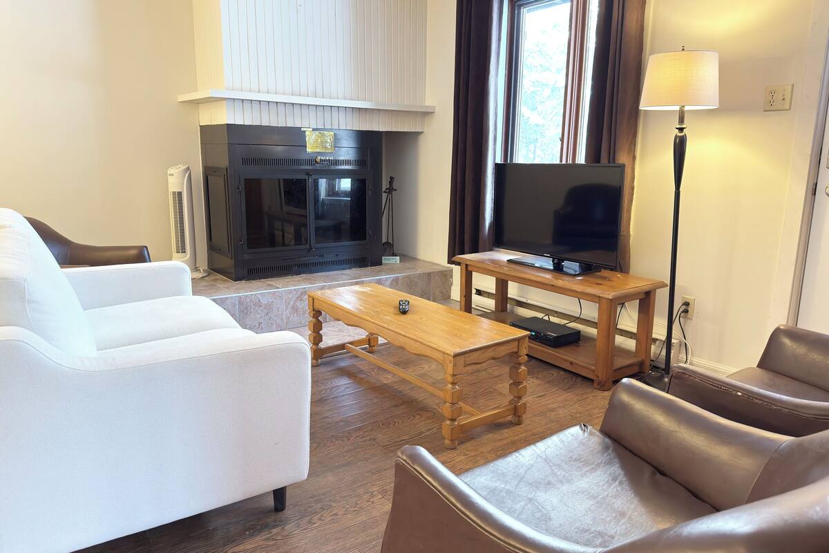 A living room with a fireplace, a television, a sofa, a coffee table, and a lamp.