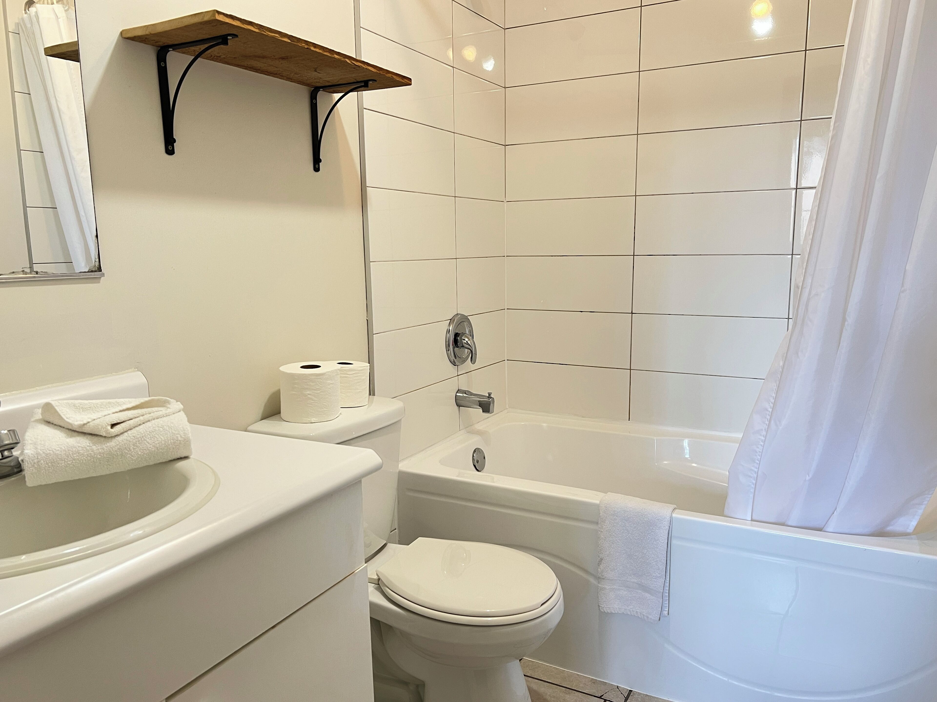 A bathroom with a toilet, sink, and bathtub. There is a towel on the sink and a towel on the bathtub.