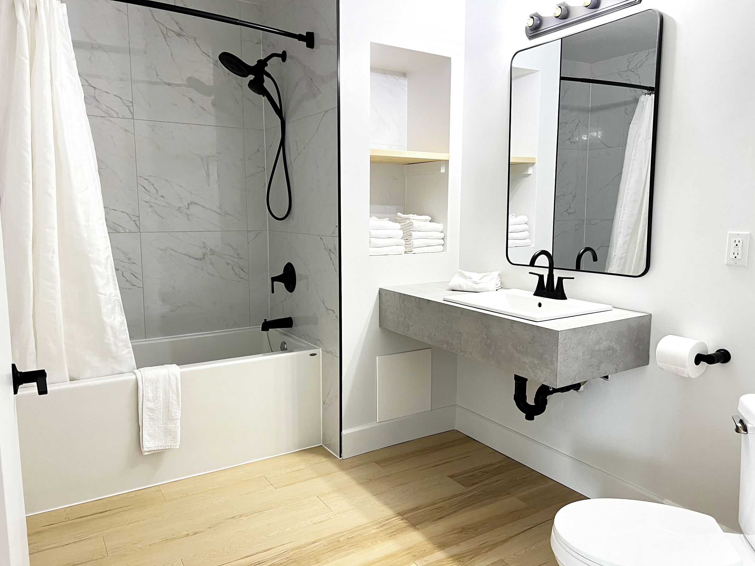 A modern bathroom with a bathtub, a shower, a sink, and a toilet.